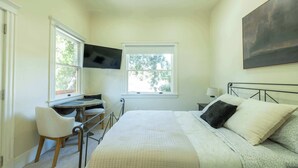 A bedroom with a bed, a desk, and two windows. - Beautiful Turn of the Century Home with Pet Friendly Yard (Martinez)