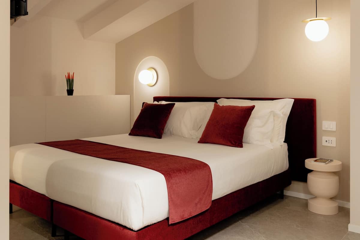 Un dormitorio moderno con una cama grande, una lámpara de pared redonda y un techo con vigas a la vista.