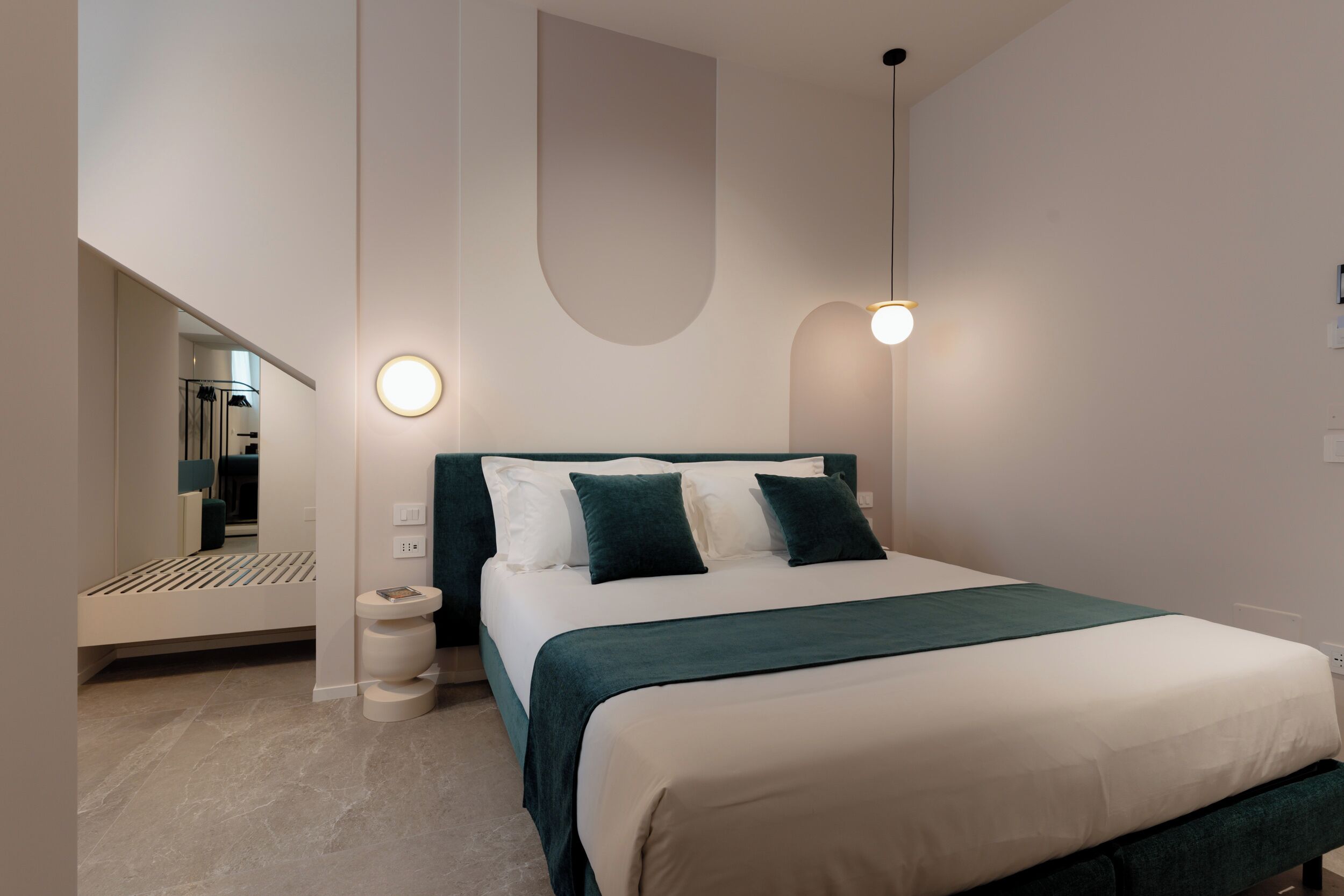 Un dormitorio moderno con una cama grande, una mesita de noche y una lámpara fijada a la pared.