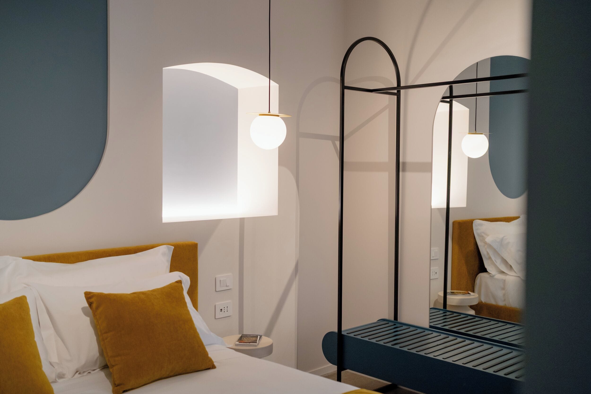 Una habitación de hotel moderna con cama, mesita de noche y espejo.