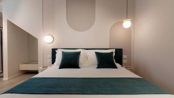 Una habitación de hotel moderna con una cama grande, dos mesitas de noche y una lámpara fijada a la pared.