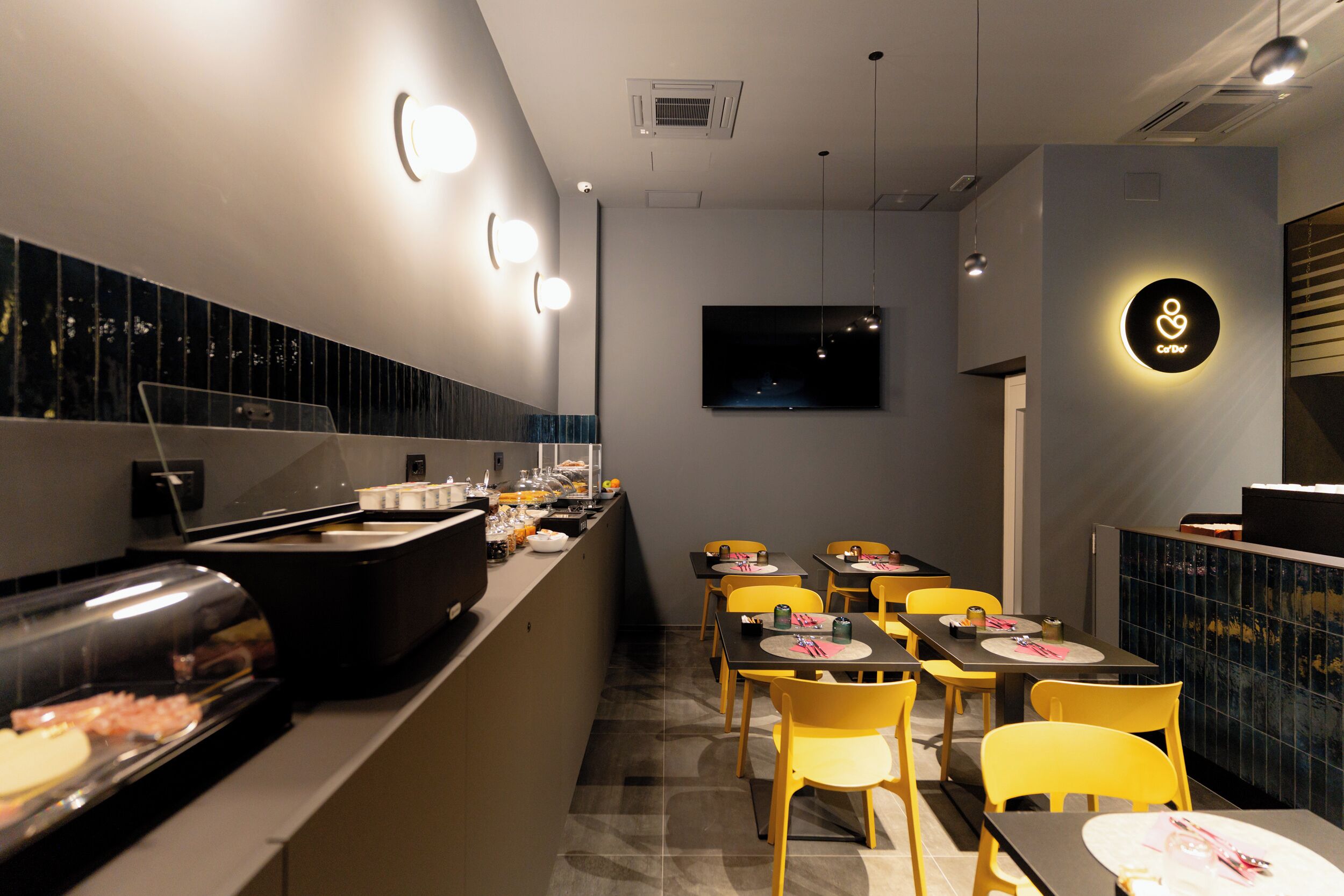 Un restaurante moderno con zona de bufé, varias mesas y sillas.