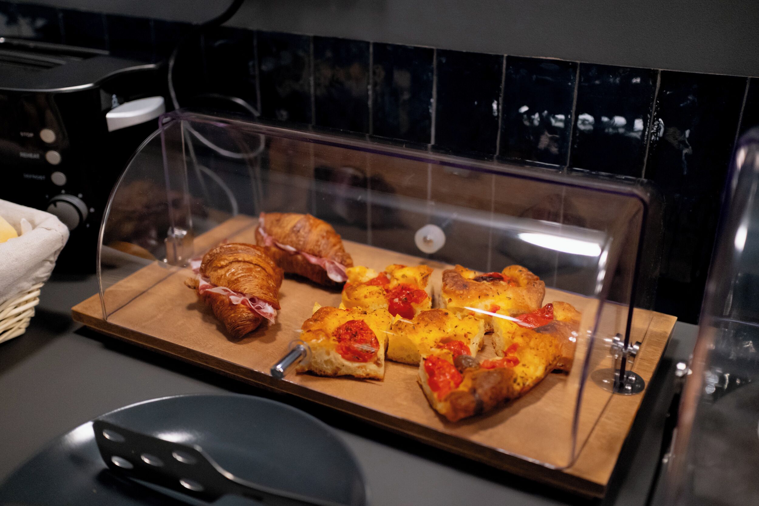 A display case with various baked goods, including croissants and pizzas, in a commercial setting.