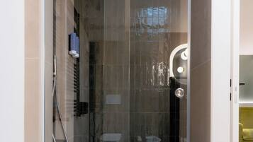 Un baño moderno con ducha acristalada, inodoro y lavamanos.