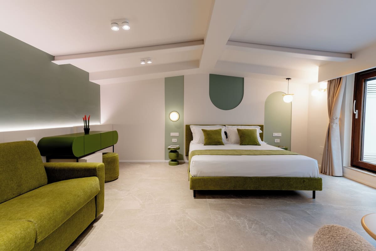 Un dormitorio moderno con una cama grande, un sofá verde y un diseño minimalista.