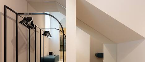 A modern, compact bedroom with a built-in wardrobe, a bench, and a slanted ceiling.