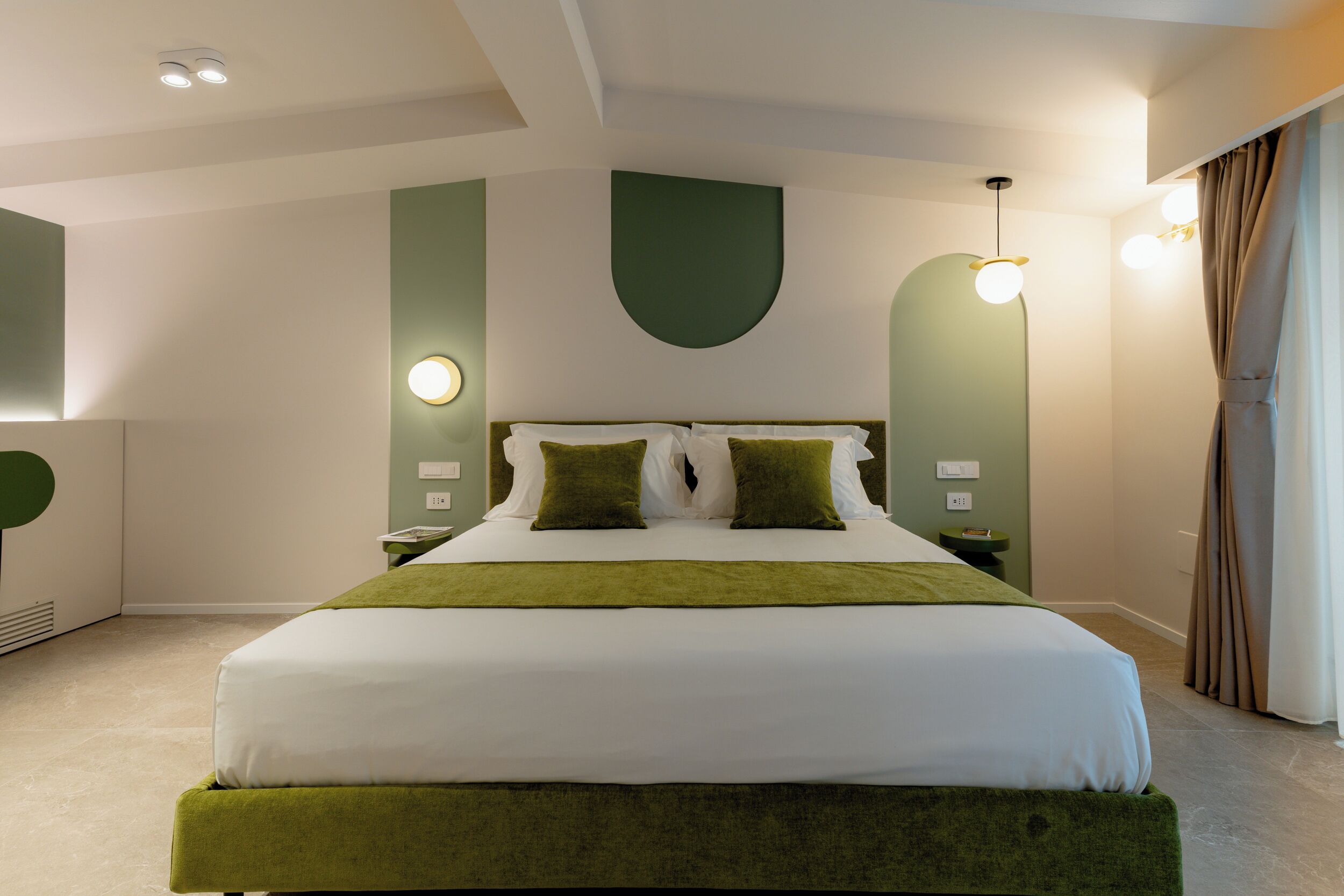 A modern hotel room with a large bed, green accents, and a unique ceiling design.