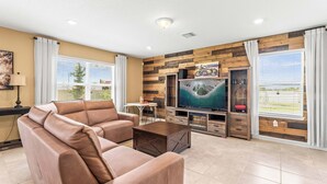 A living room with a leather sofa, a coffee table, a flat-screen TV, and wooden panel walls. - Happy Daze Home for 8 (Davenport)