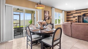 A dining area with a round table, chairs, and a hanging light fixture. - Happy Daze Home for 8 (Davenport)