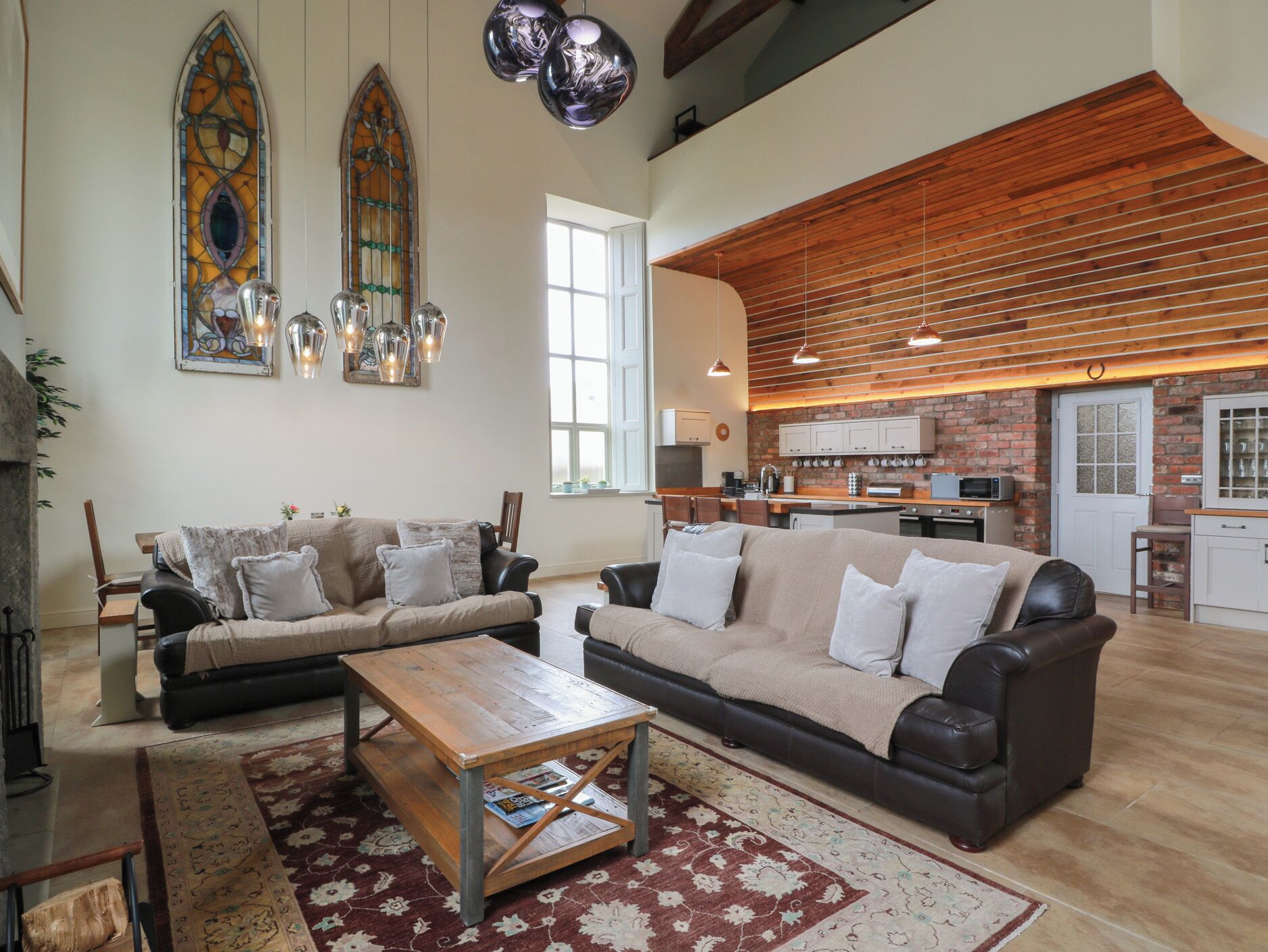 A spacious living area with a large sofa set, a wooden coffee table, and a patterned rug.