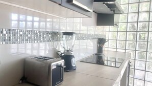 Une cuisine moderne équipée d’un grille-pain, d’un mixeur et d’une fenêtre donnant sur un paysage verdoyant.