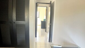 Une chambre d’hôtel avec un lit, un bureau et une chaise. Une porte donne accès à une autre pièce.