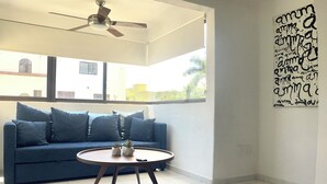 Un salon avec un canapé bleu, une table basse ronde et un ventilateur de plafond.