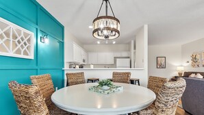 Un coin repas avec une table ronde, des chaises en osier et un lustre.