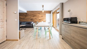 Una cocina moderna con una pared de madera, una mesa de comedor con sillas, un sofá y un televisor.