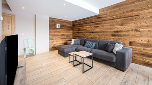 Una sala moderna con un sofá modular, una mesita de madera y un televisor.