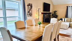 A dining area with a wooden table and chairs, a fireplace, and a TV mounted on the wall.