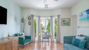 Ein modernes Wohnzimmer mit einem grünen Sofa, einem Holzschrank und einem Esstisch mit einem Stuhl.