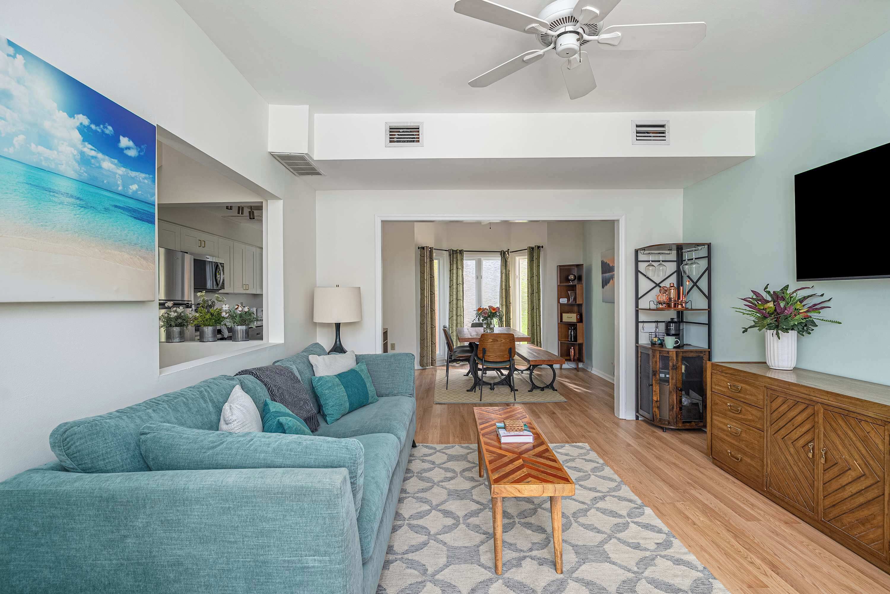 Un salon moderne avec un canapé de couleur turquoise, une table basse en bois et un ventilateur de plafond.