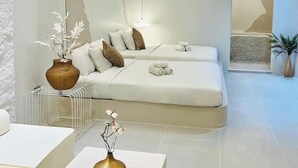 A modern, minimalist room with a sofa bed, white furniture, and decorative vases.
