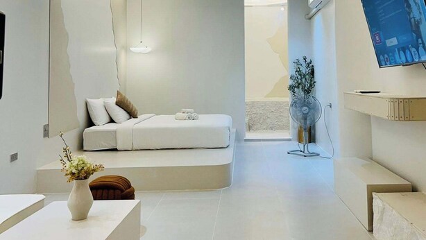 A modern living room with a white sofa, a coffee table, and a TV mounted on the wall.
