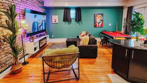Una sala de estar moderna con televisor de pantalla plana, mesa de billar y una zona de estar confortable.