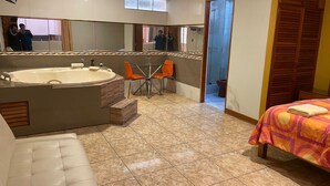 Ein modernes Badezimmer mit einer großen Badewanne, einer separaten Duschkabine und einem kleinen Tisch mit Stühlen.
