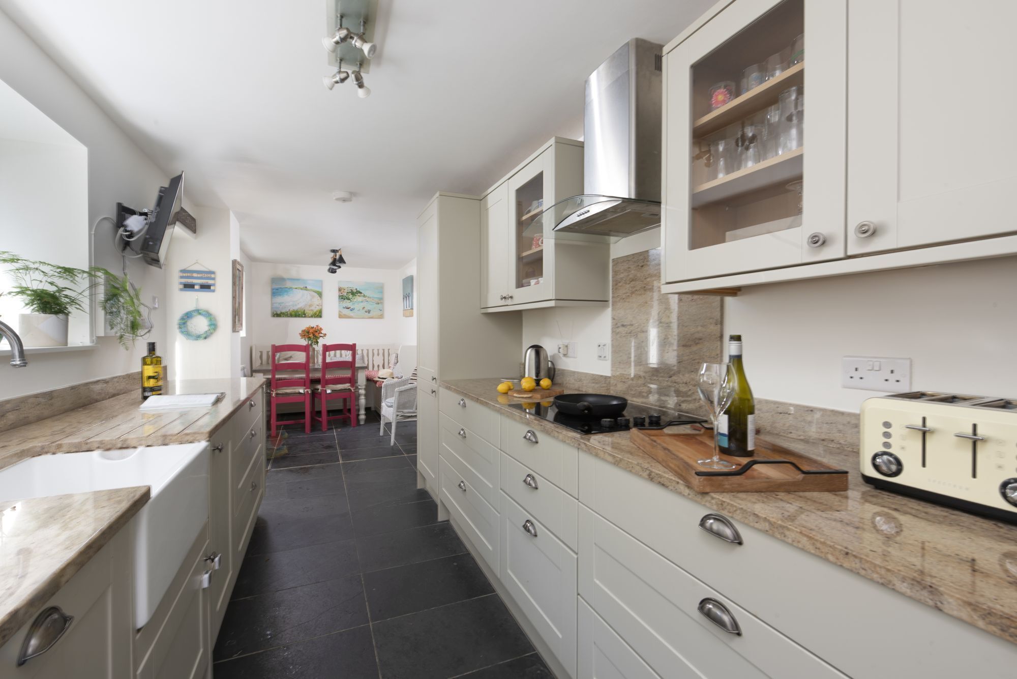 A modern kitchen with white cabinets, a marble countertop, a stove, and a vintage toaster.