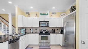 Una cocina con armarios blancos, electrodomésticos de acero inoxidable y una isla central con lavavajillas.