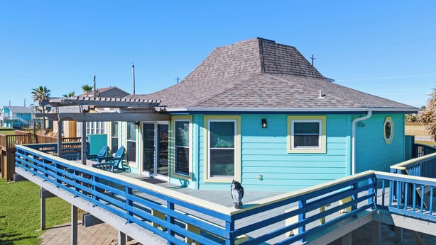 Una casa de dos pisos con fachada azul y terraza de madera.