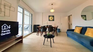 A modern living room with a TV, dining area, and a sofa.
