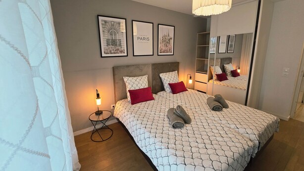 A bedroom with a bed, a bedside table, a mirror, and wall art.