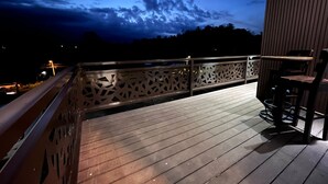 A wooden deck with a railing, a table, and a chair. - Barefoot (Bijagua de Upala)