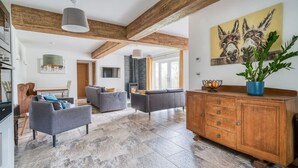 Uma sala de estar ampla com lareira, móveis modernos e vigas de madeira aparente.