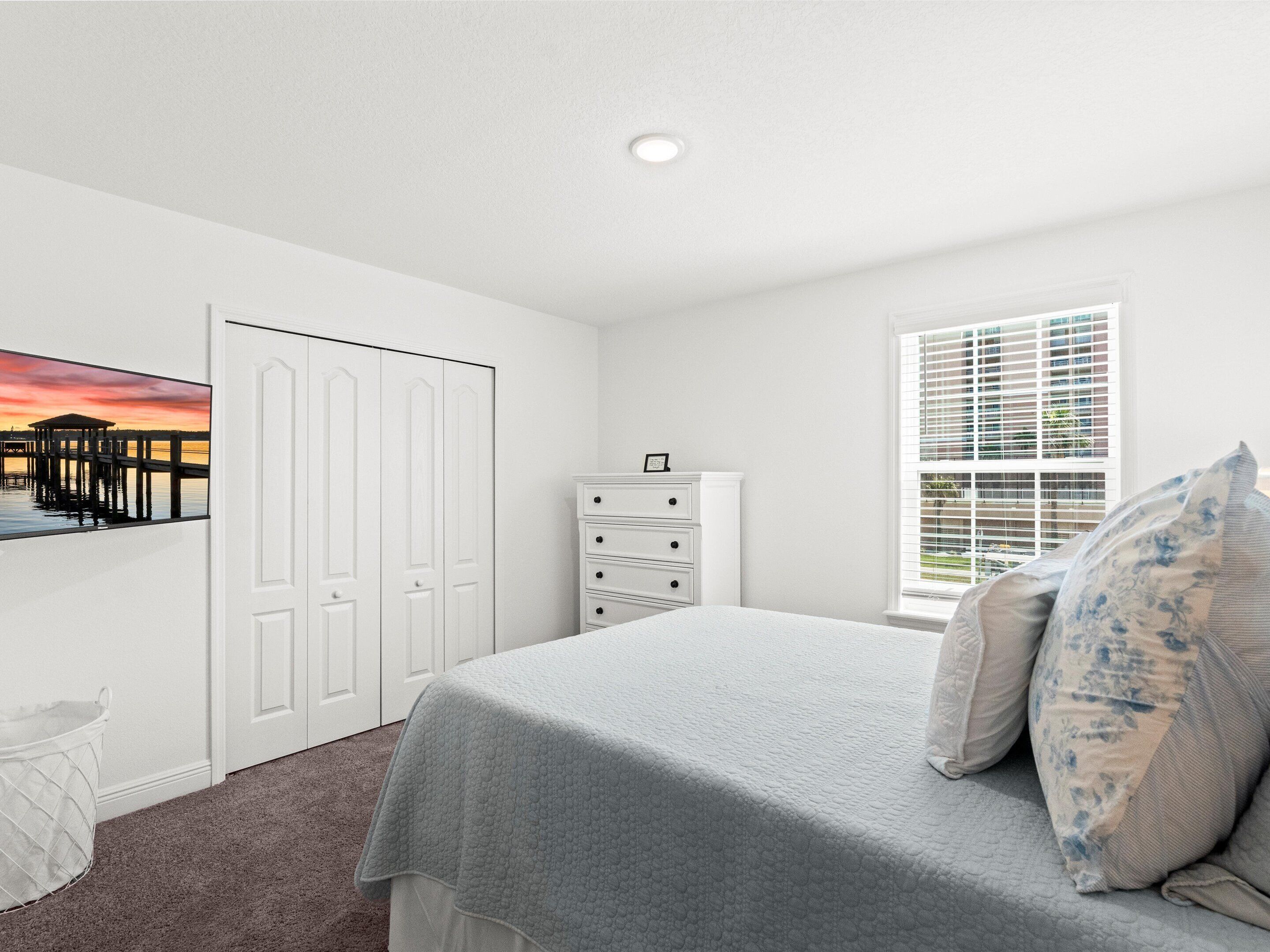 Un dormitorio con cama, cómoda, ventana con persianas y un cuadro en la pared.