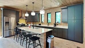 A modern kitchen with a central island, stainless steel appliances, and wooden cabinetry.