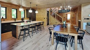 A spacious kitchen with a central island, wooden walls, and a staircase leading to an upper level.