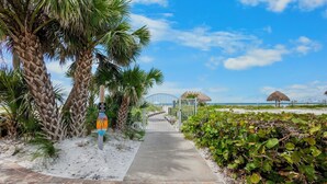 A pathway leading to a beach area with palm trees and a gate. - Peppertree #507- Private Access (Siesta Key)