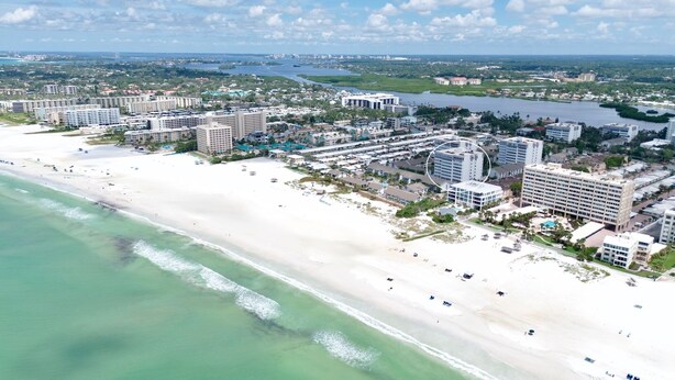 An aerial view of a coastal resort area with multiple high-rise hotels, a sandy beach, and a river. - Peppertree #507- Private Access (Siesta Key)