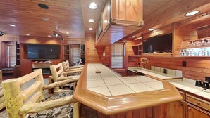 Un interior de madera con una zona de bar, asientos y un televisor.
