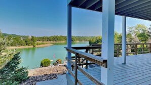 Una terraza de madera con vistas a un lago tranquilo y un cielo despejado.