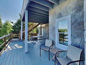 A covered deck with a stone wall, a table, and chairs. - Tranquil Cove by Jackson Mountain Rentals (Sevierville)