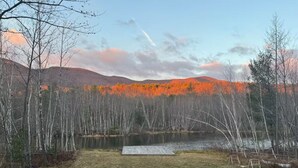 A lakeside outdoor area with a fire pit and chairs, surrounded by trees and a view of mountains. - The Moon House Dome: 10 min away from skiing and golfing. Waterfront. Fishing. (Acra)