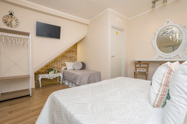 A bedroom with a bed, a TV, a clock, a mirror, and a staircase.