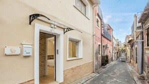 Una calle estrecha con un edificio que tiene una puerta, una ventana y un letrero.