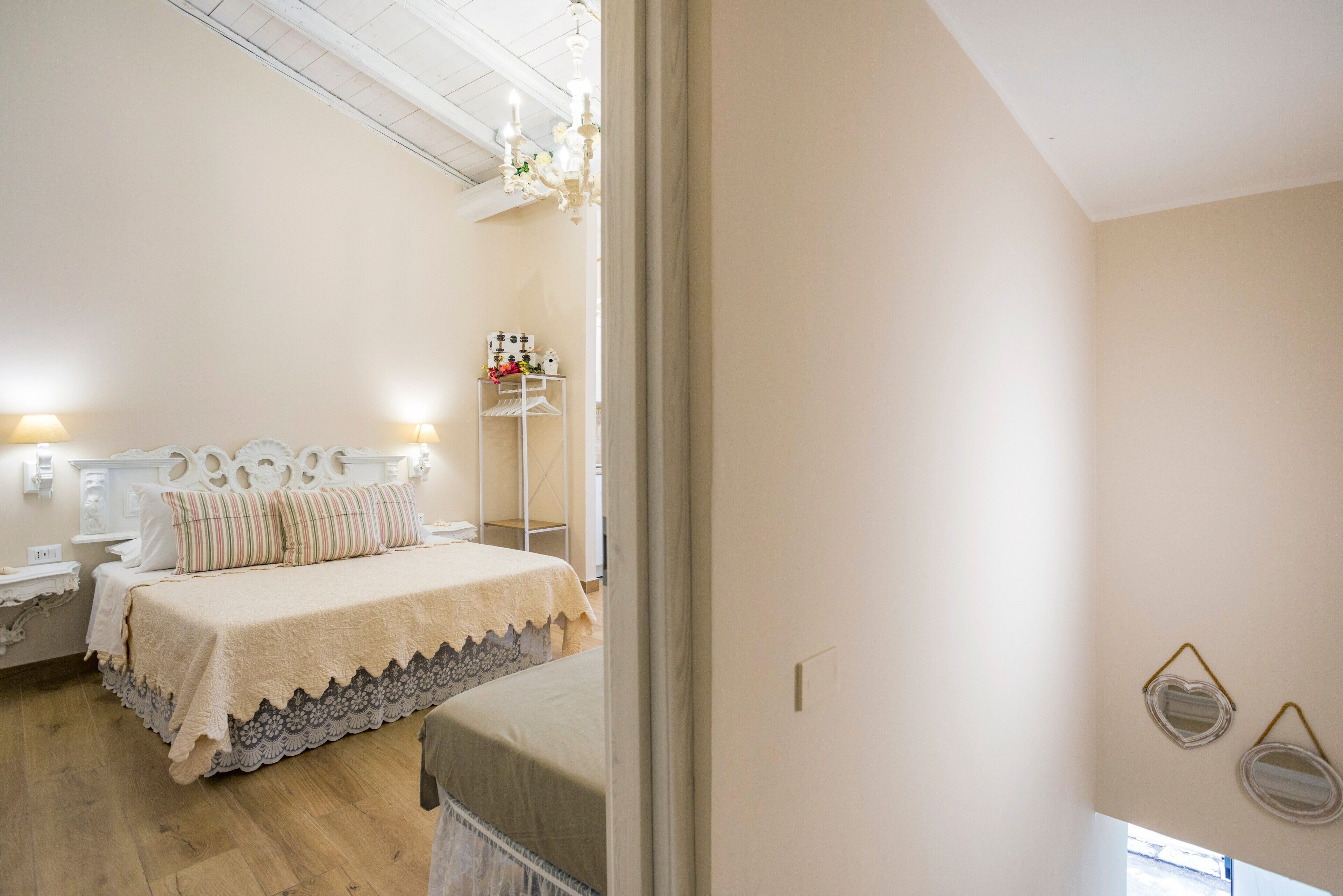 Un dormitorio con cama, mesitas de noche, cómoda y estante con objetos decorativos.