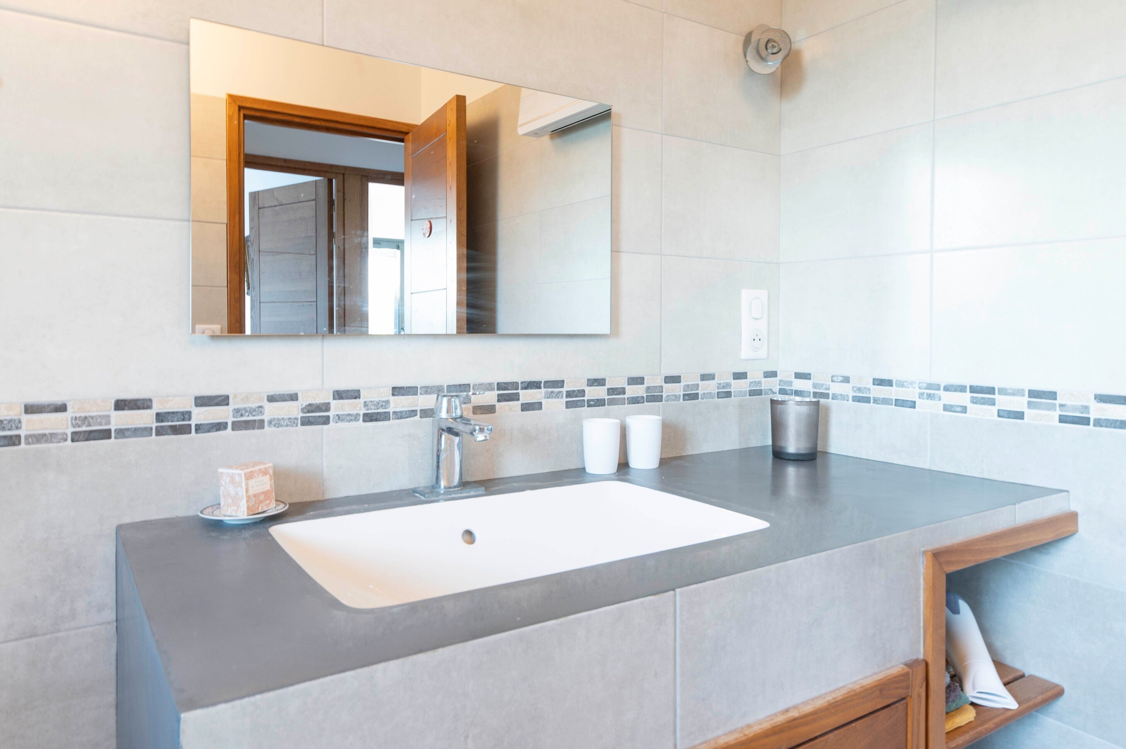 A bathroom with a large mirror, a sink, and a shower area.