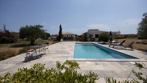 A swimming pool with lounge chairs and a table, surrounded by greenery and a building in the background. - Guest Room "Room 2" with Mountain View, Shared Pool and Wi-Fi (Aléria)