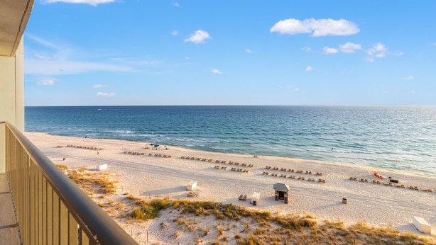 A beach view from a balcony with a clear sky, sandy beach, and ocean. - 702 | Cozy Fall Beachfront Retreat—1BR, Gulf Views, Pool & VIP Beach Service (Panama City Beach)