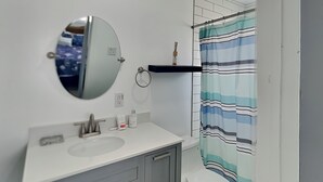 Un bagno con un lavandino bianco, uno specchio rotondo, una tenda da doccia a righe e un water.